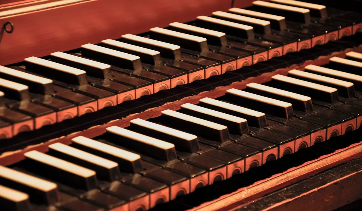 Close-up of the black and white keys on a wooden pipe organ with two stacked keyboards.