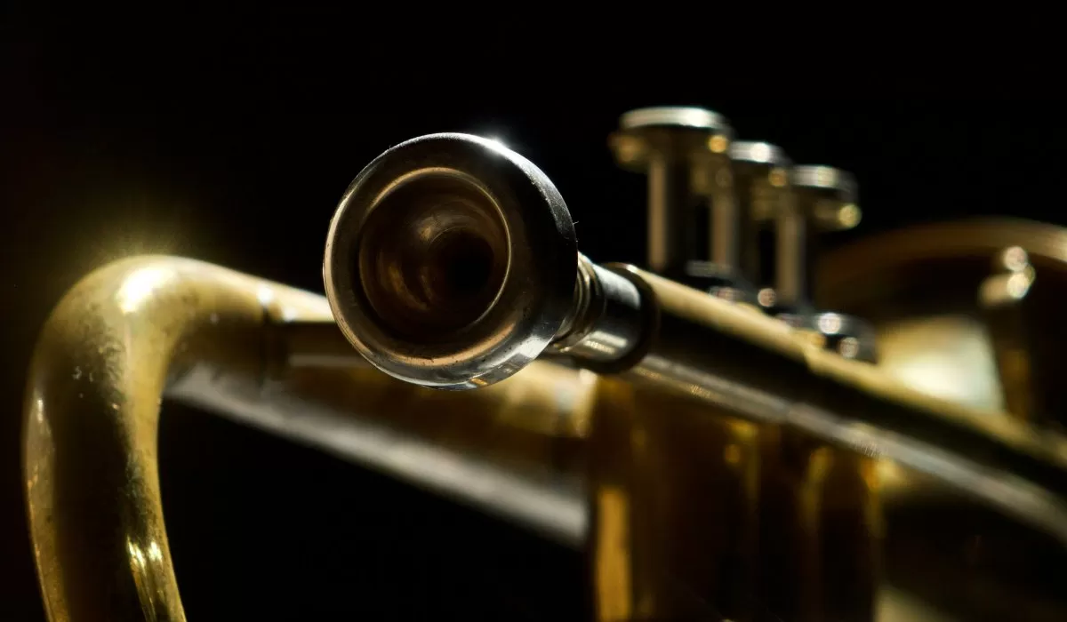 Close-up of a brass trumpet with its bell facing the camera against a dark background.
