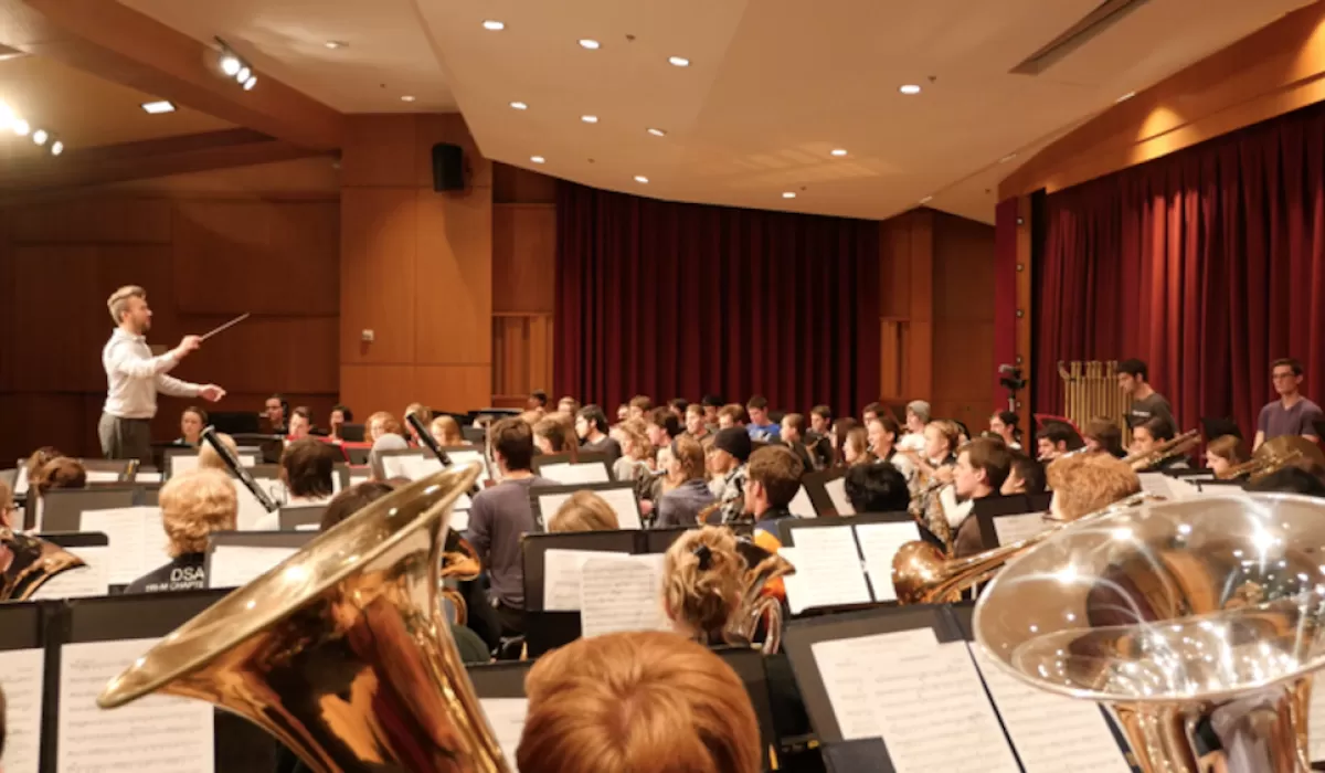 Conductor leading a student concert band rehearsal in Grusin Music Hall.