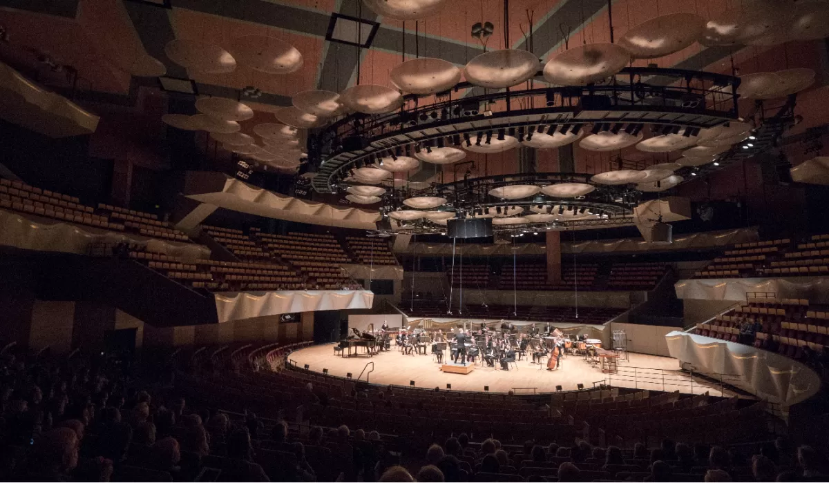Boettcher Concert Hall with an orchestra performing onstage and audience members seated in the foreground.