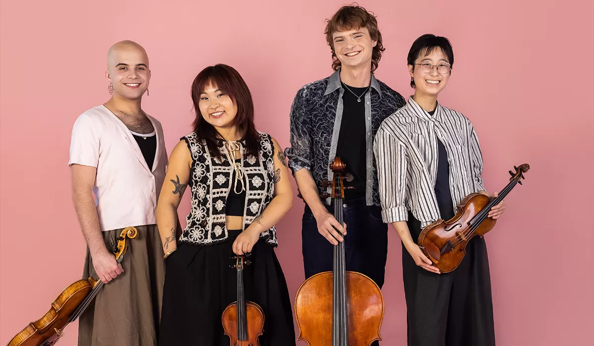 Four members of a string quartet sitting down with instruments.