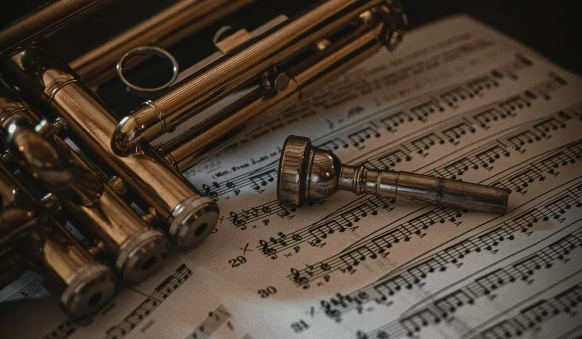 Close-up of brass trumpets and a trumpet mouthpiece resting on sheet music.