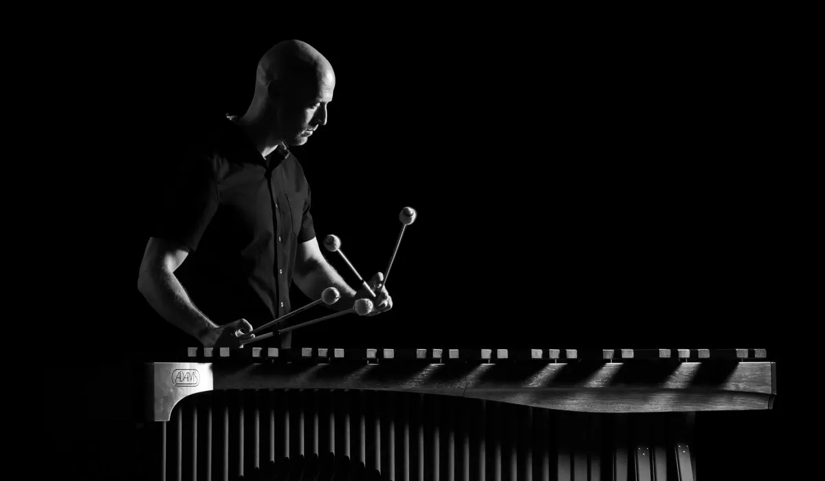 Black-and-white photo of a musician playing a vibraphone with four mallets.