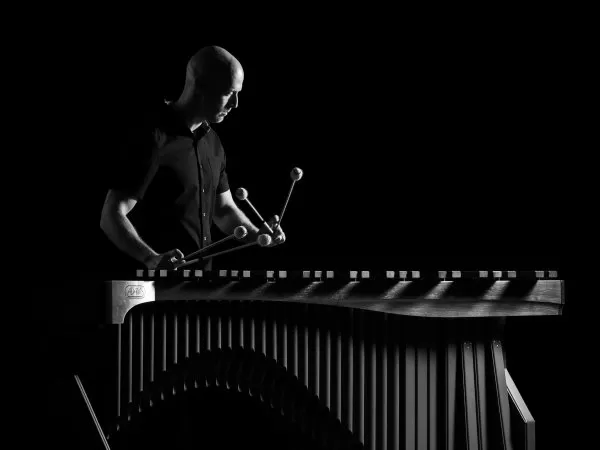 Black-and-white photo of a musician playing a vibraphone with four mallets.