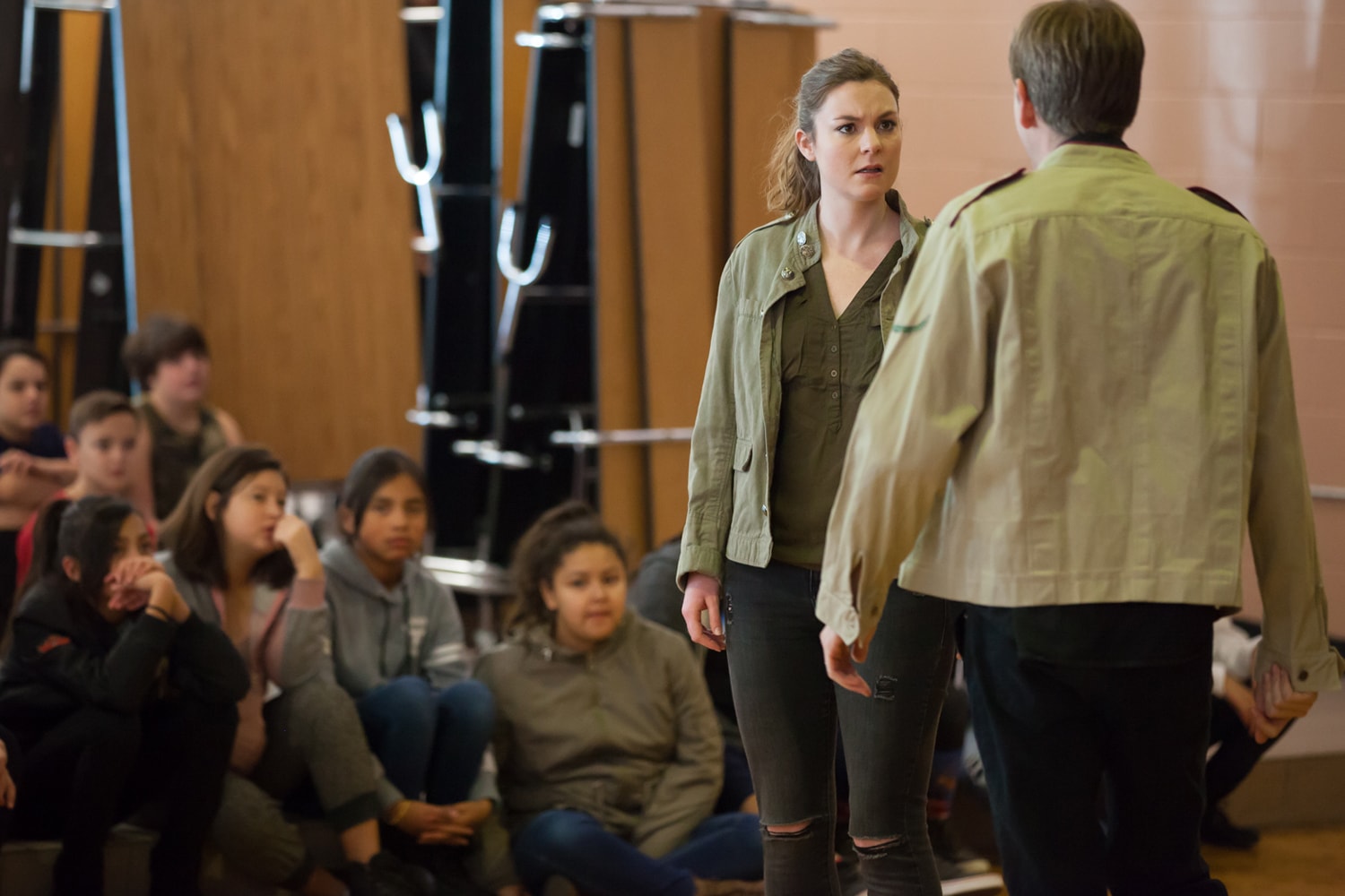 Actors in classroom facing each other while children watch.