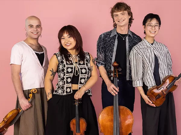 Four members of a string quartet sitting down with instruments.