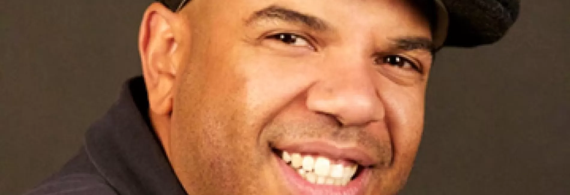 A smiling man wearing a hat