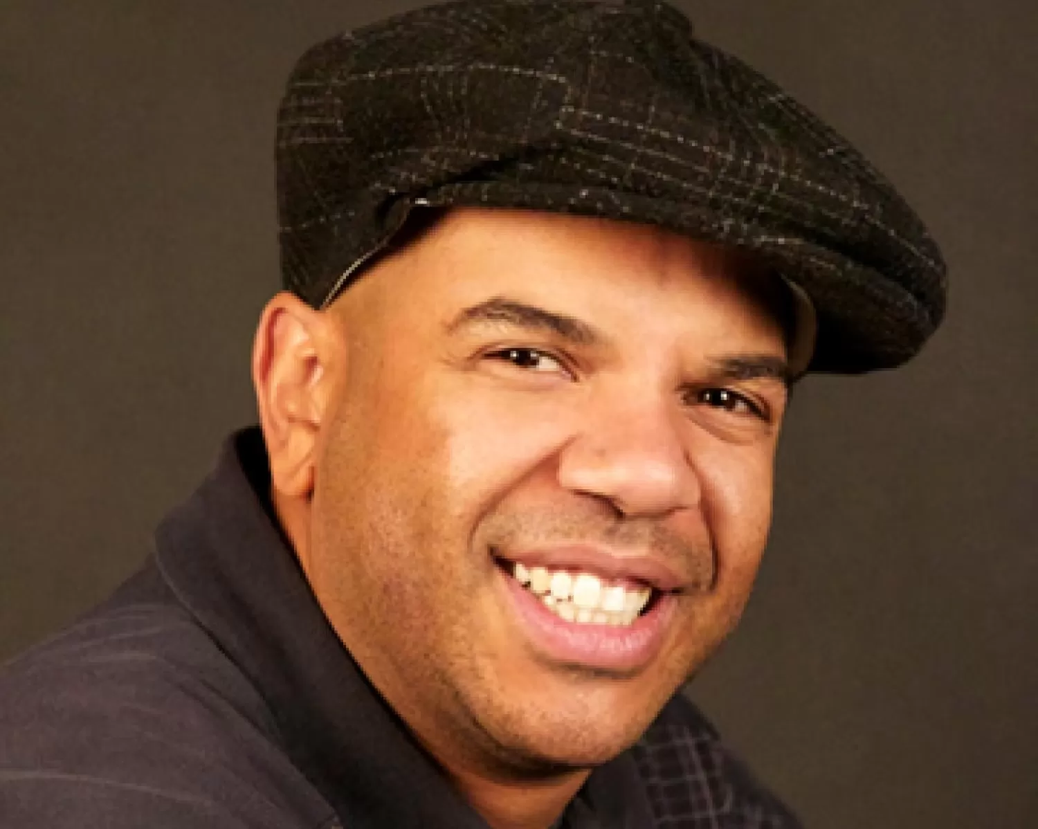 A smiling man wearing a hat