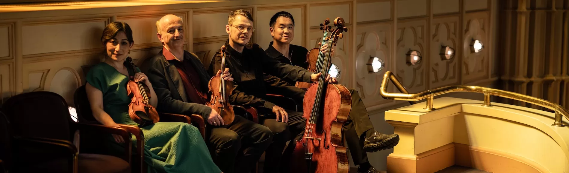 Four string players in a vintage auditorium