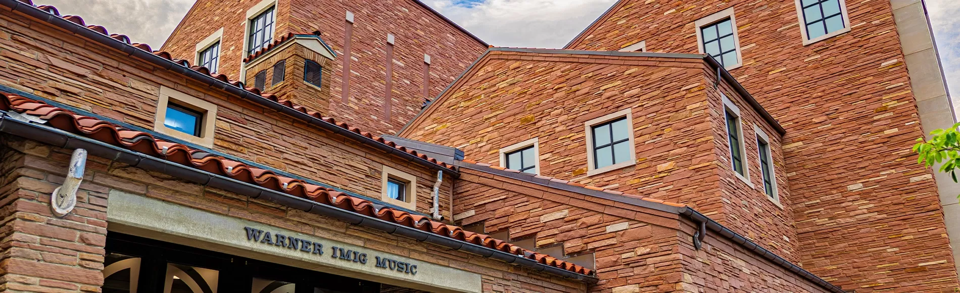 View looking upward at modern red stone building with several stories.