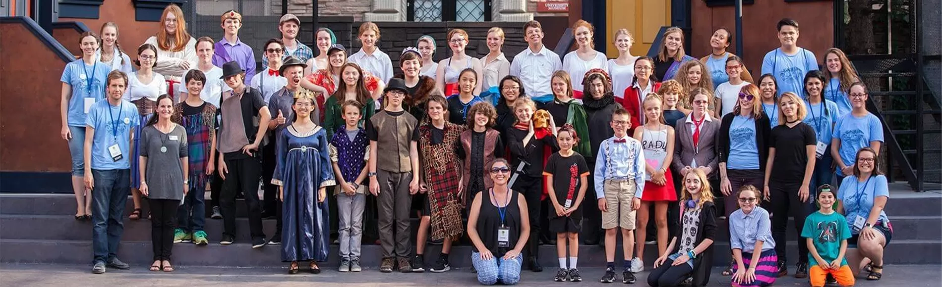A large group photo of children in theatrical costumes who are attending a camp.